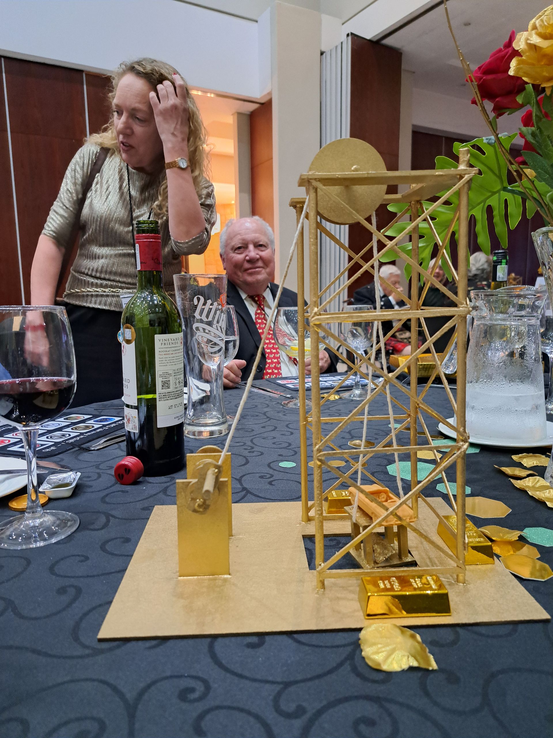 Tabletop Eiffel Tower model with champagne bottle, wine glass, and red flowers at a party table
