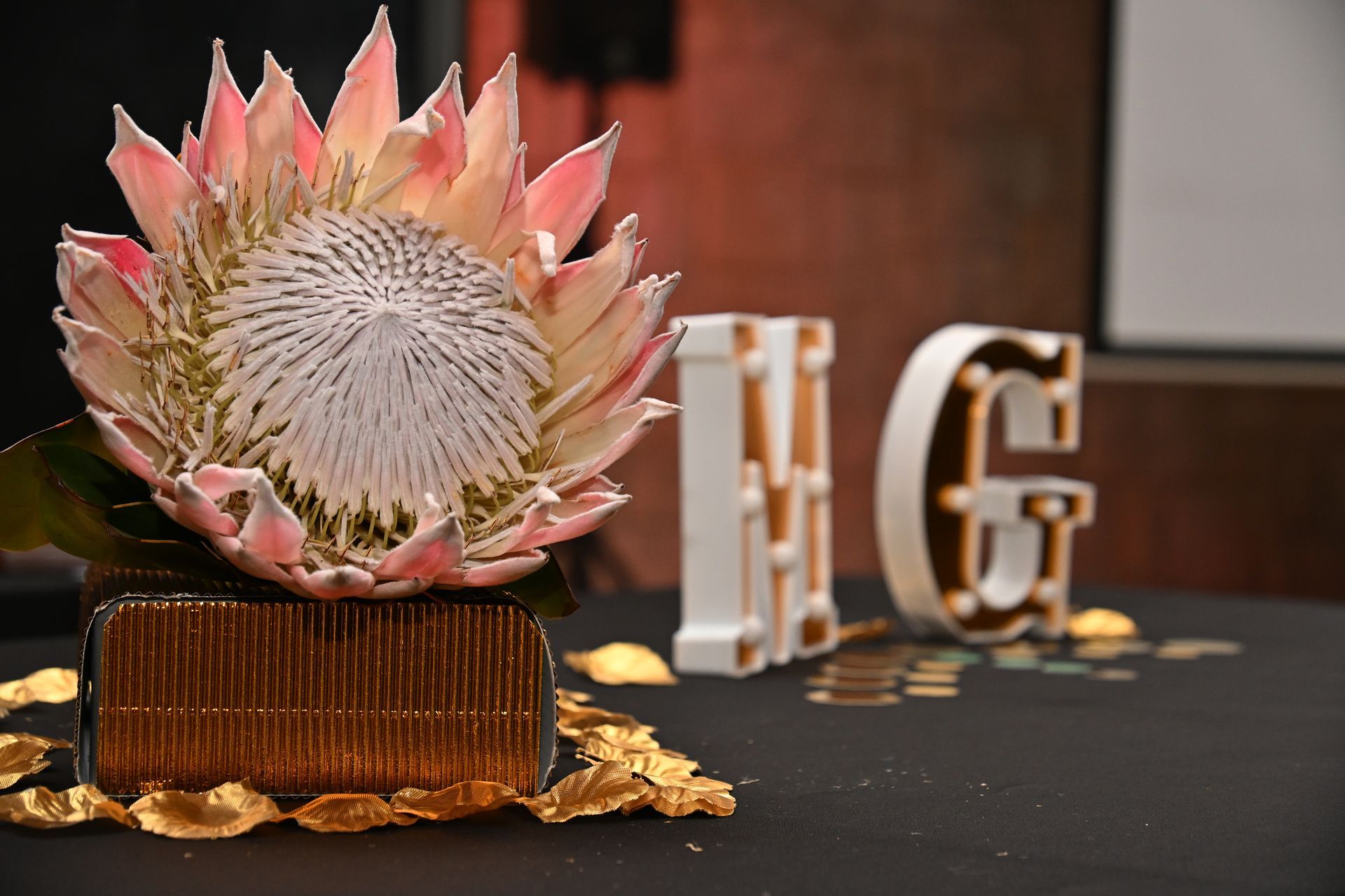 Decorative flower centerpiece on a table with gold letters in the background