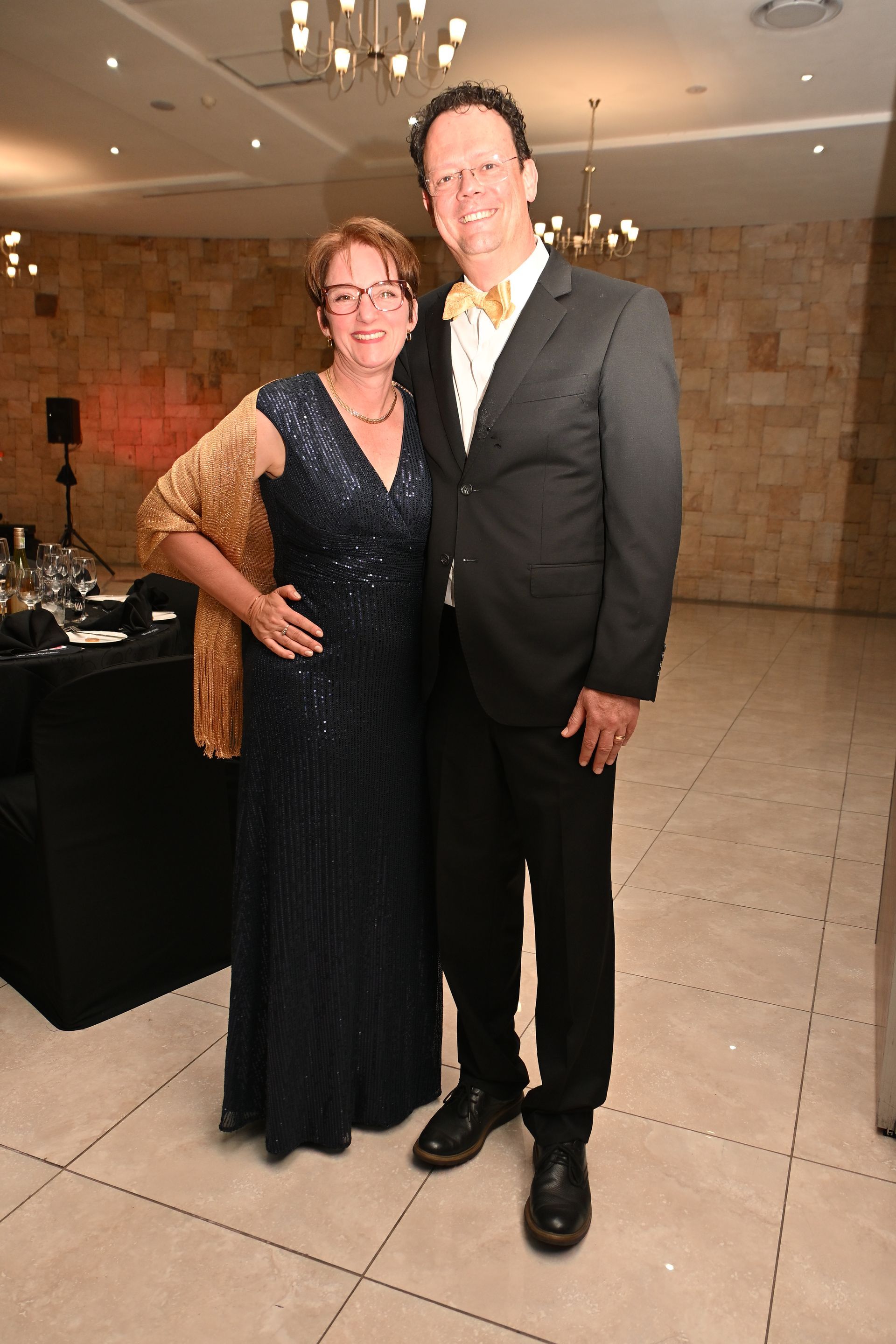 Two people in formal attire posing together at an indoor event.