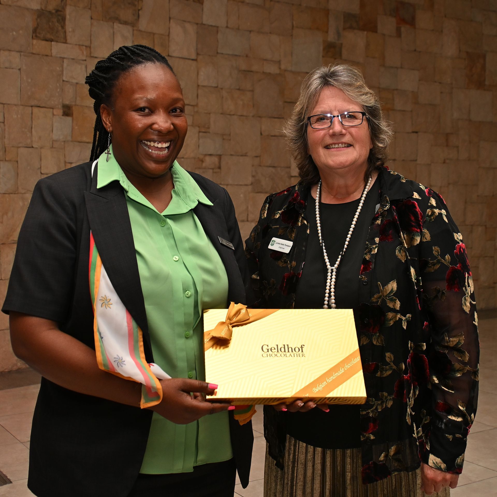 Two women smiling, holding a certificate at an awards ceremony