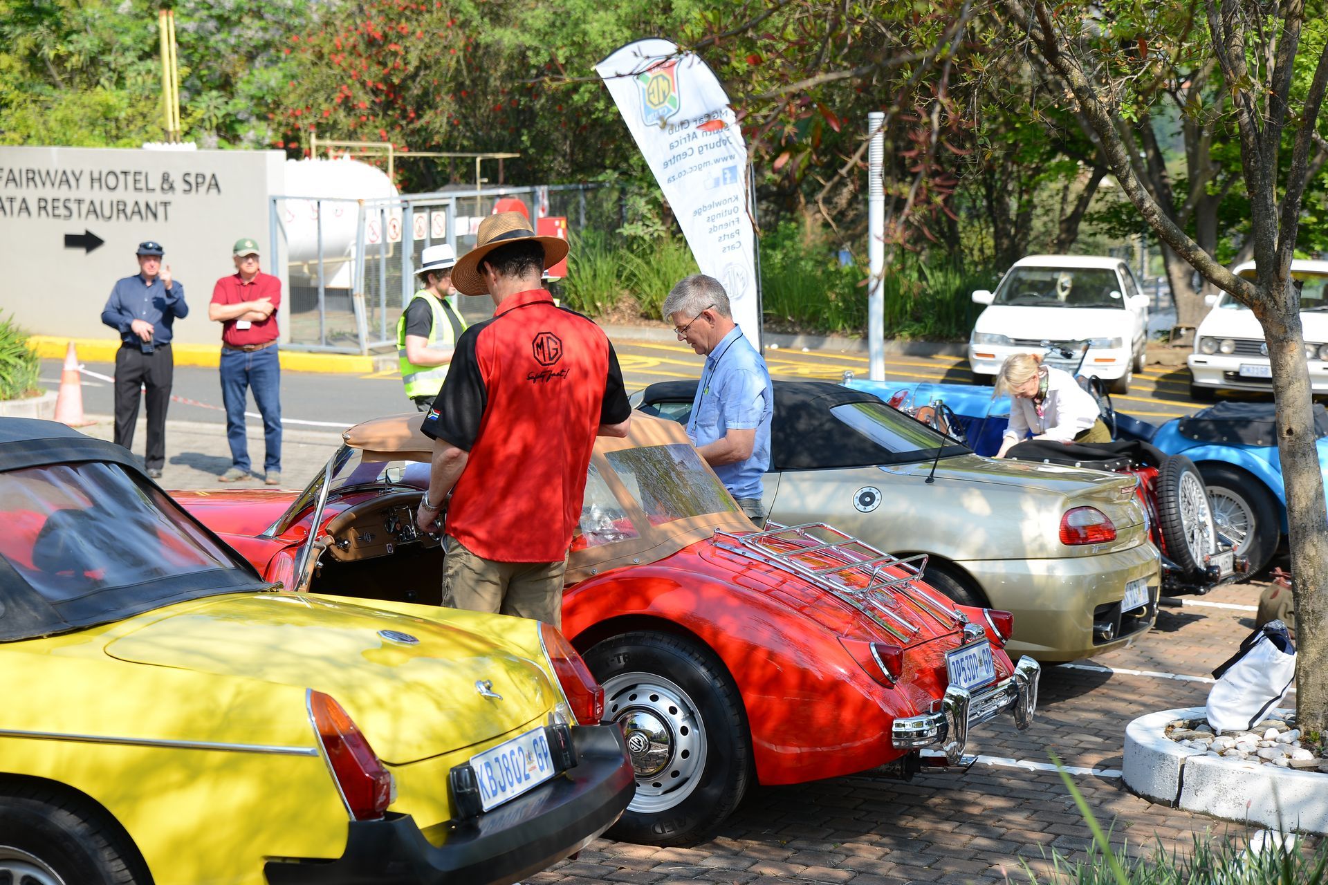 People gathered around colorful vintage cars at an outdoor auto show.
