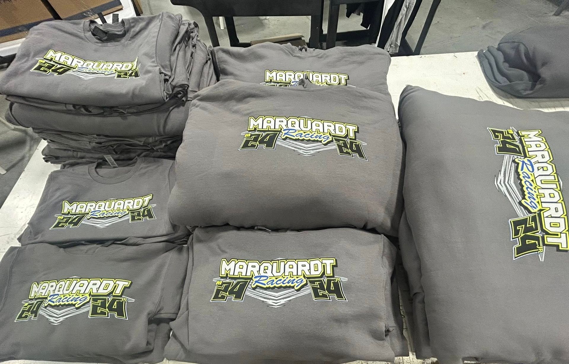 Stacks of folded grey hoodies featuring a green and white