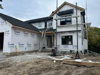 Partially constructed white house with scaffolding and Tyvek wrap 