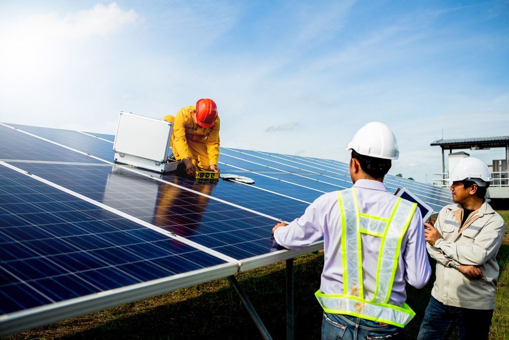 Two Men Are Working On A Solar Panel In A Field — PRO Solar & Electrical In Port Stephens, NSW