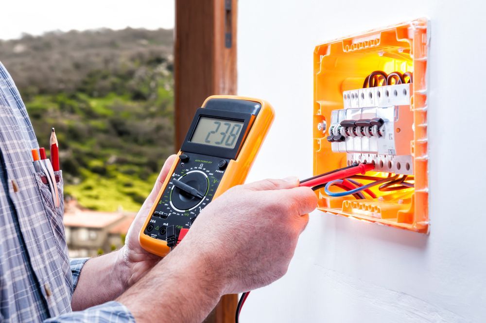 An Electrician Is Using A Digital Multimeter To Test An Electrical Box — PRO Solar & Electrical In Lake Macquarie, NSW