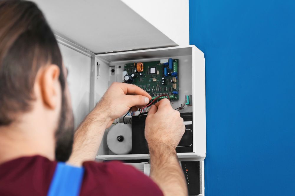 A Man Is Working On A Security System With A Screwdriver — PRO Solar & Electrical In Maitland, NSW
