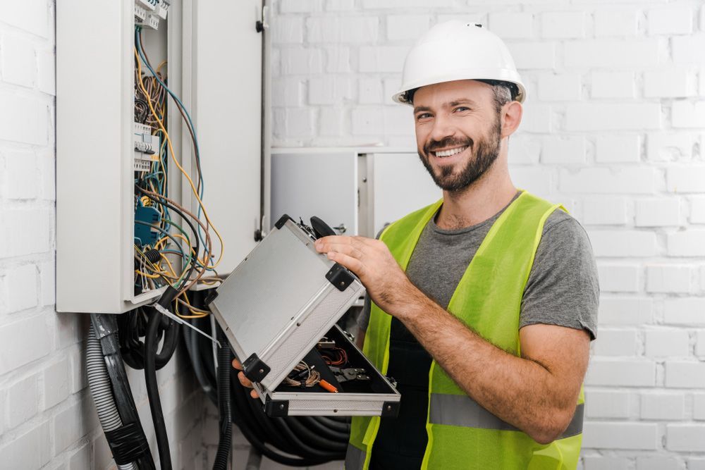 Electrician holding toolbox near electrical box — Electricians Near Me in Newcastle NSW