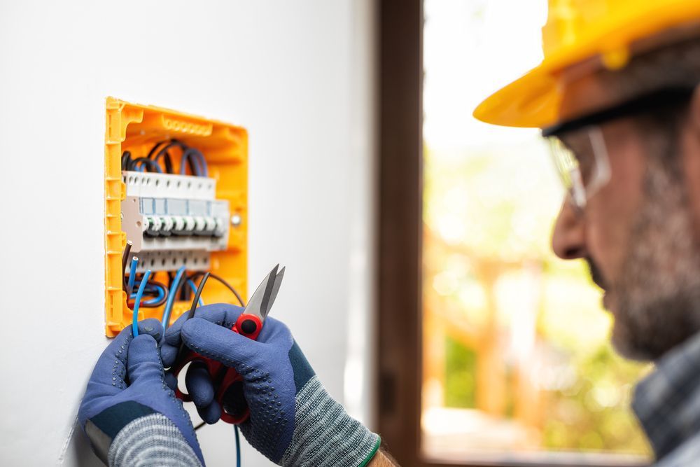 An Electrician Is Working On An Electrical Box On A Wall — PRO Solar & Electrical In Lake Macquarie, NSW