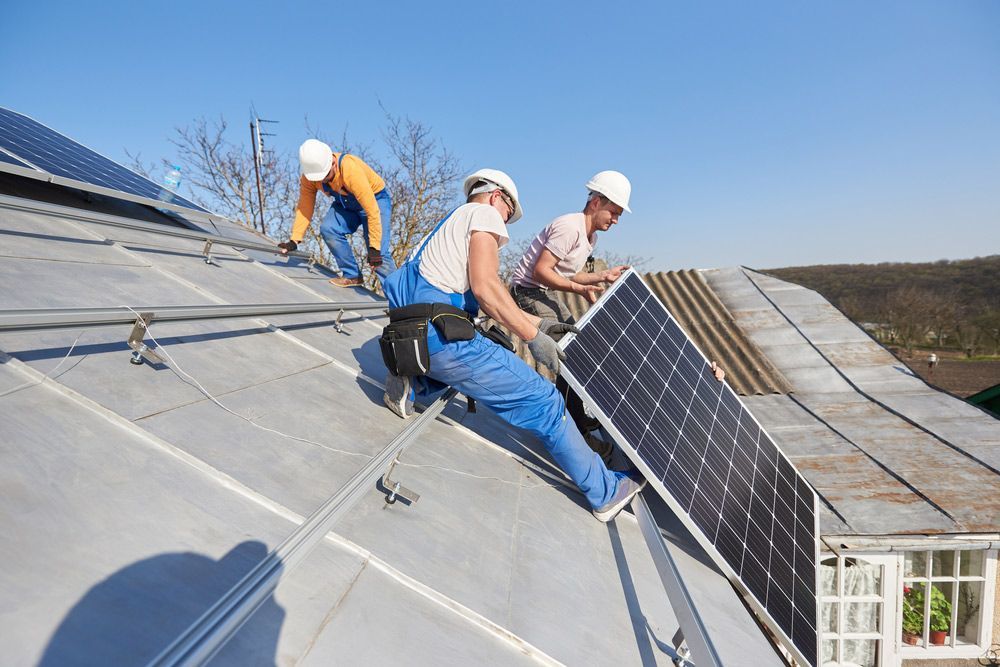 A Group Of Men Are Installing Solar Panels On A Roof — PRO Solar & Electrical In Port Stephens, NSW