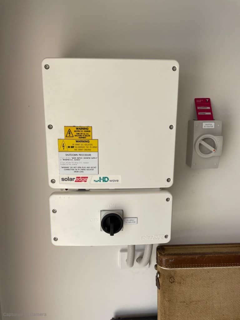 A White Box With A Yellow Sticker On It Is Hanging On A Wall Next To A Switch — PRO Solar & Electrical In Lake Macquarie, NSW