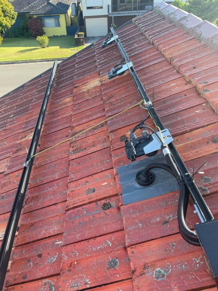 A Solar Panel Is Sitting On Top Of A Tiled Roof — PRO Solar & Electrical In Lake Macquarie, NSW