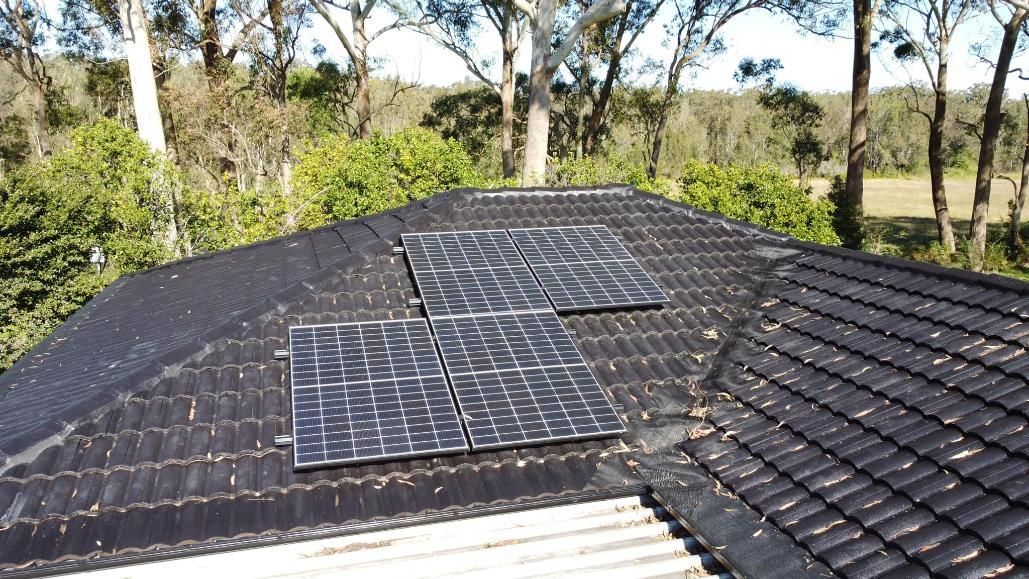 A Roof With Solar Panels On It And Trees In The Background — PRO Solar & Electrical In Port Stephens, NSW