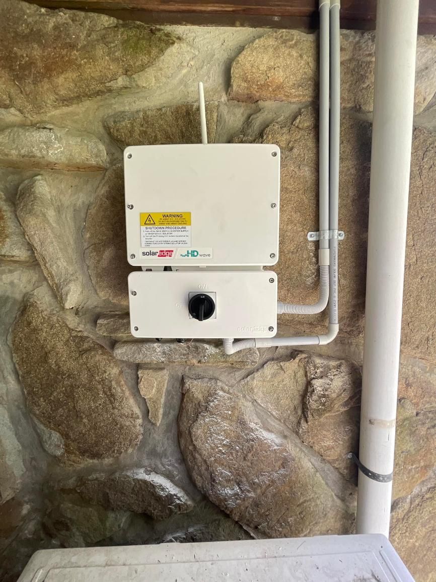 A White Box Is Sitting On A Stone Wall Next To A Pipe — PRO Solar & Electrical In Lake Macquarie, NSW