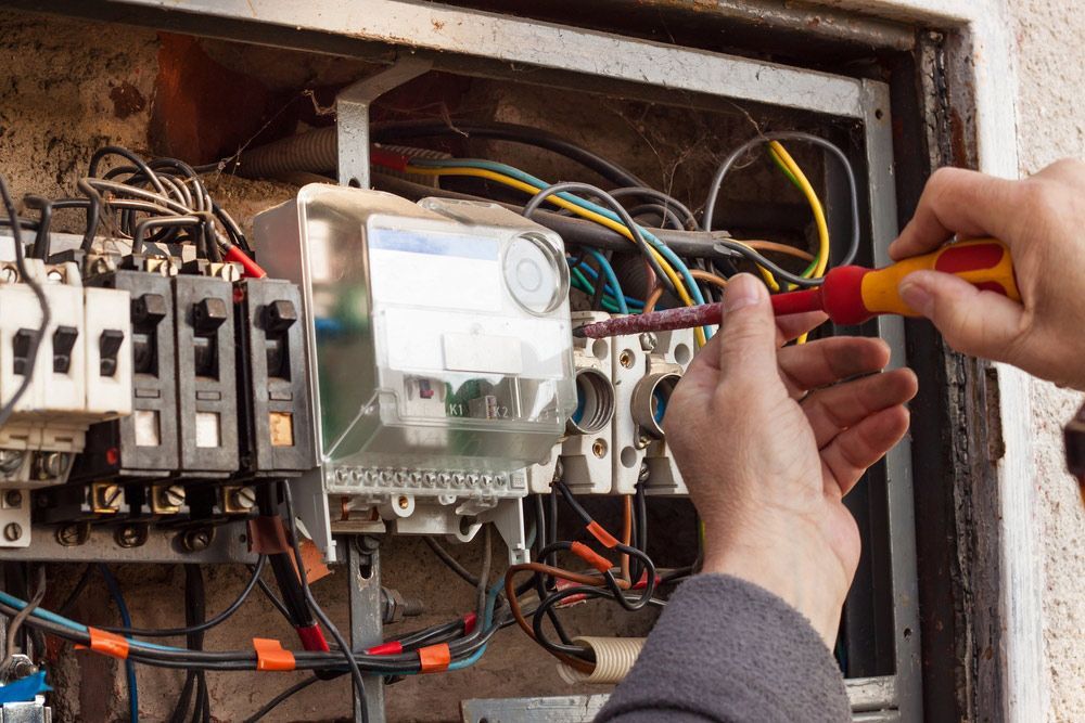 A Person Is Working On An Electrical Box With A Screwdriver — PRO Solar & Electrical In Lake Macquarie, NSW