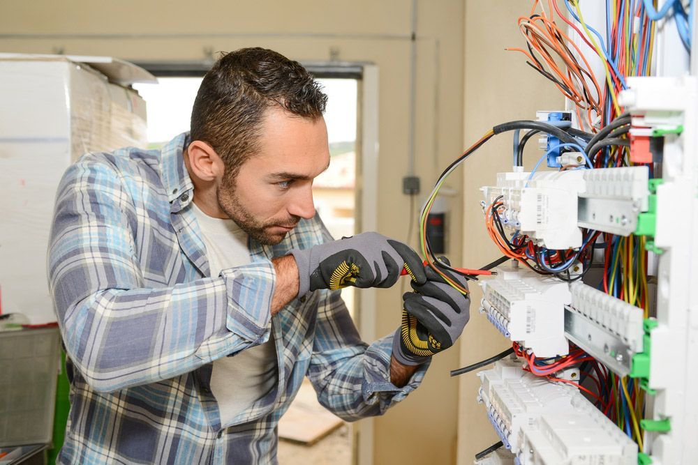 A Man Is Working On An Electrical Box With A Screwdriver — PRO Solar & Electrical In Newcastle, NSW