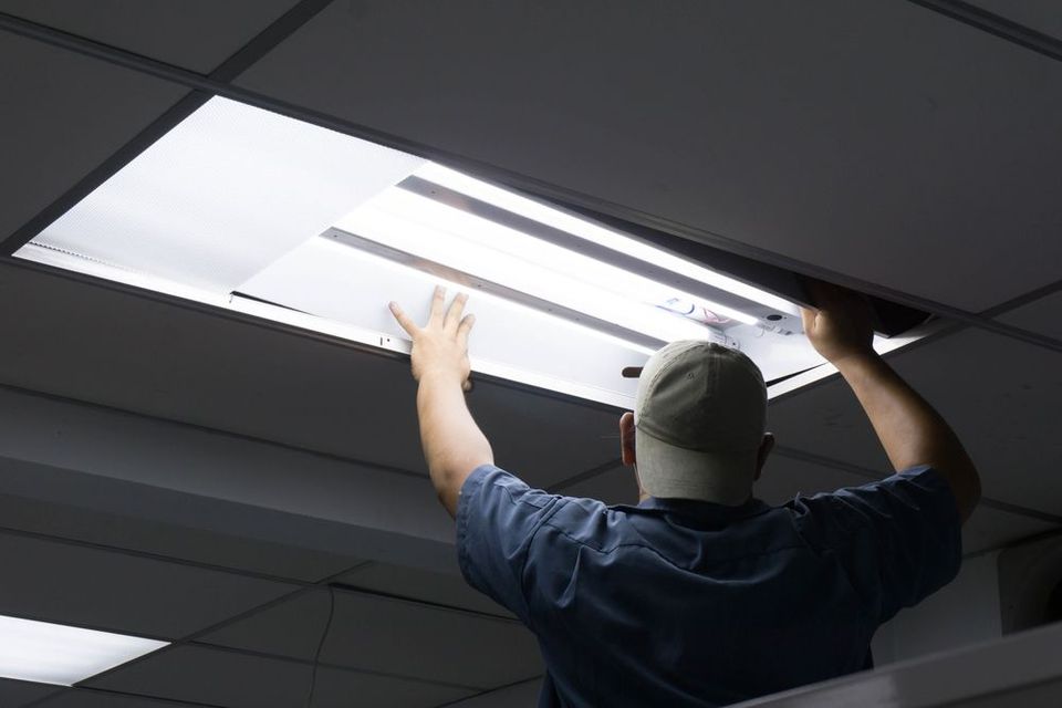 An Electrician Changing Fluorescent Light Tube — PRO Solar & Electrical In Maitland, NSW