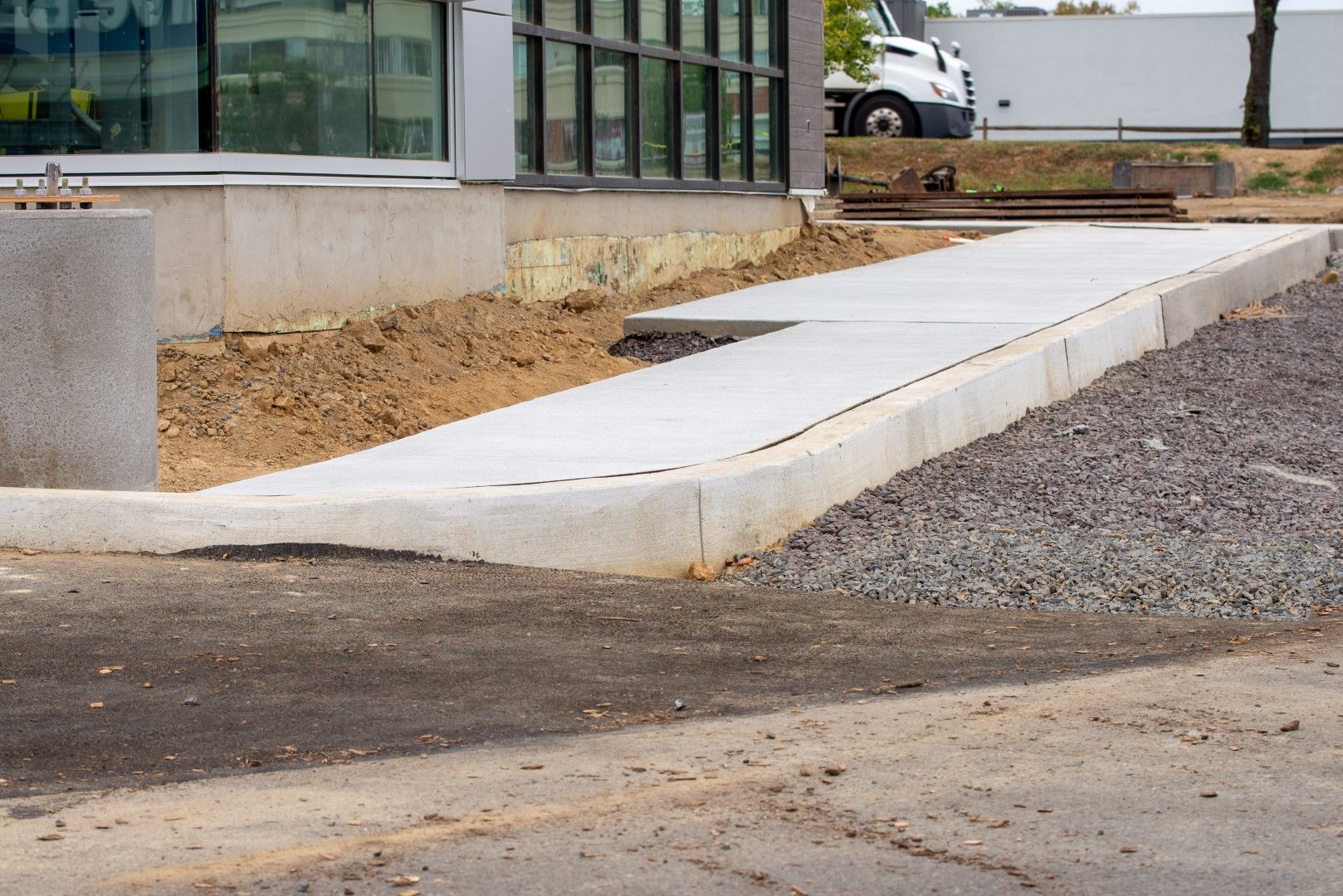 Concrete ramp leading up to a building's entrance, with gravel and dirt surrounding it.