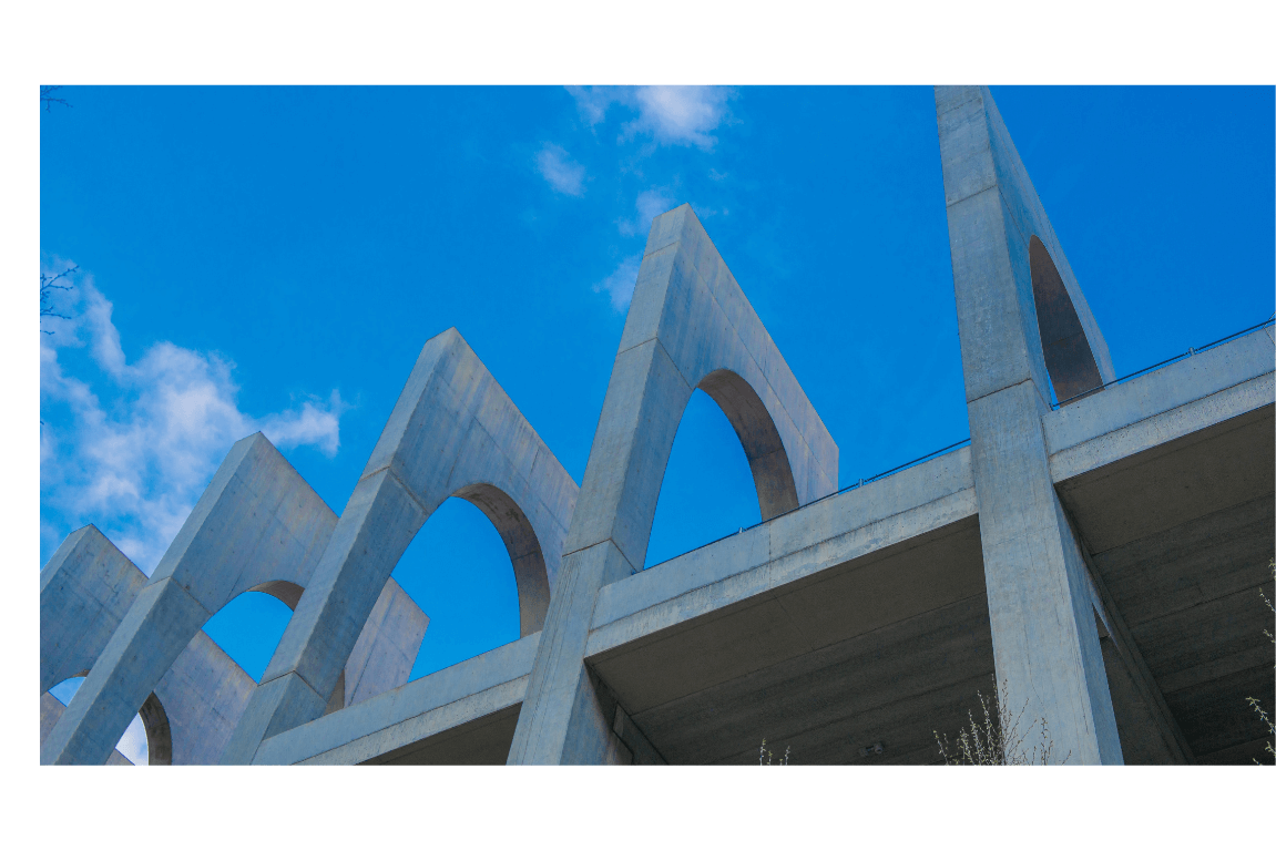 Modern concrete building with pointed arches against a bright blue sky