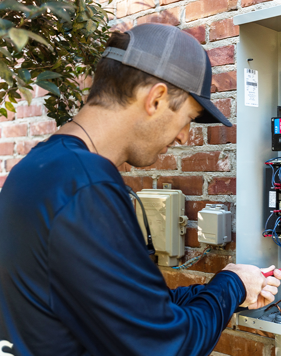 A man wearing a hat is working on a brick wall