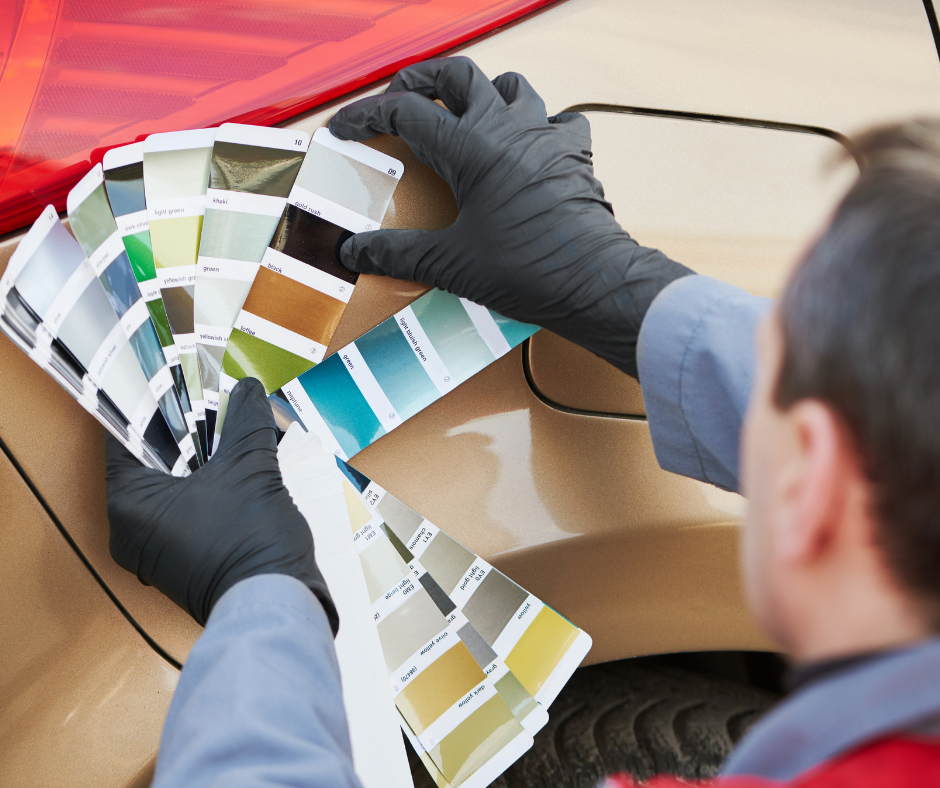 Person in black gloves comparing paint color swatches on a car door panel