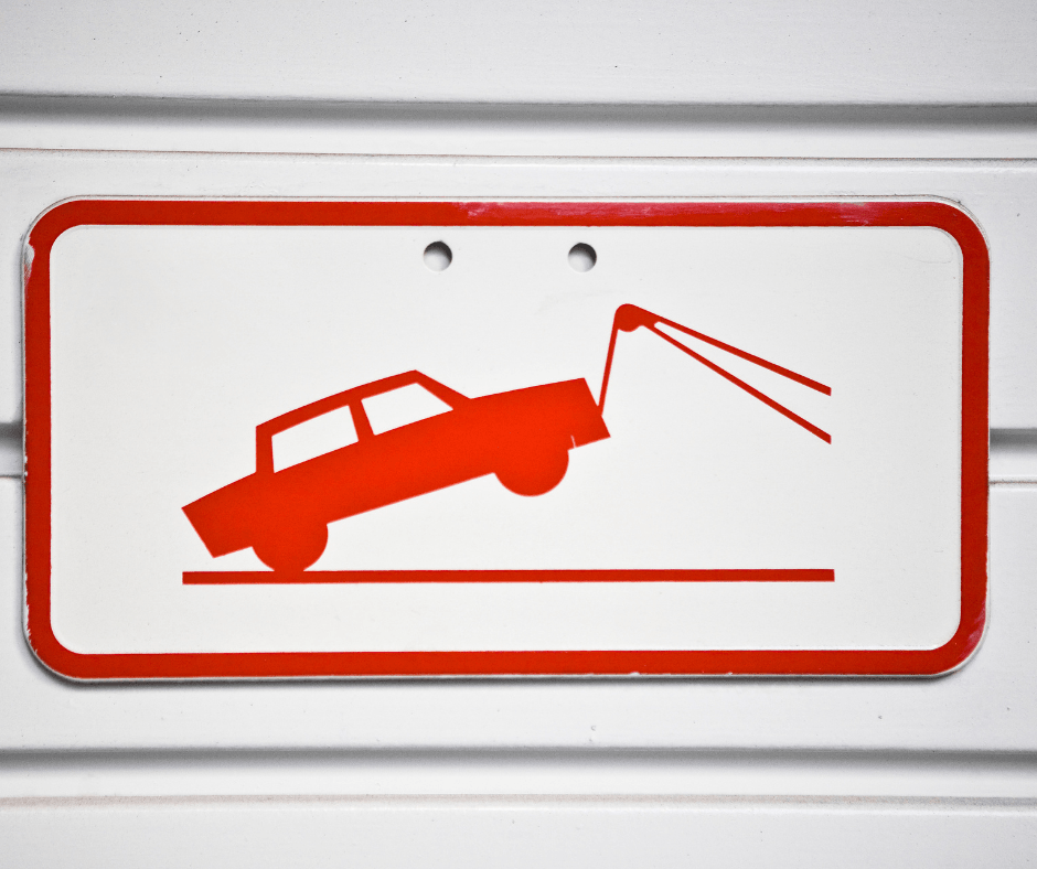 Red tow-truck warning sign with a car being lifted by a tow cable