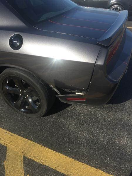 Gray sports car parked on asphalt with yellow lines, rear quarter view, black wheel and red taillight