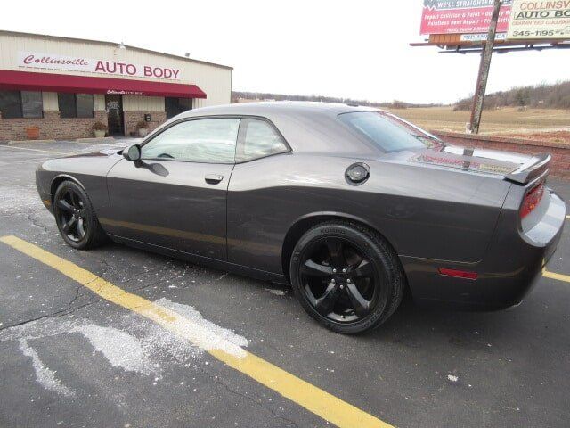 Black sports coupe parked outside an auto body shop on a wet lot