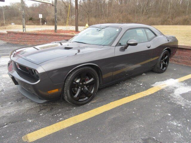 Dark gray Dodge Challenger parked in a lot with yellow lines and snow on the ground.
