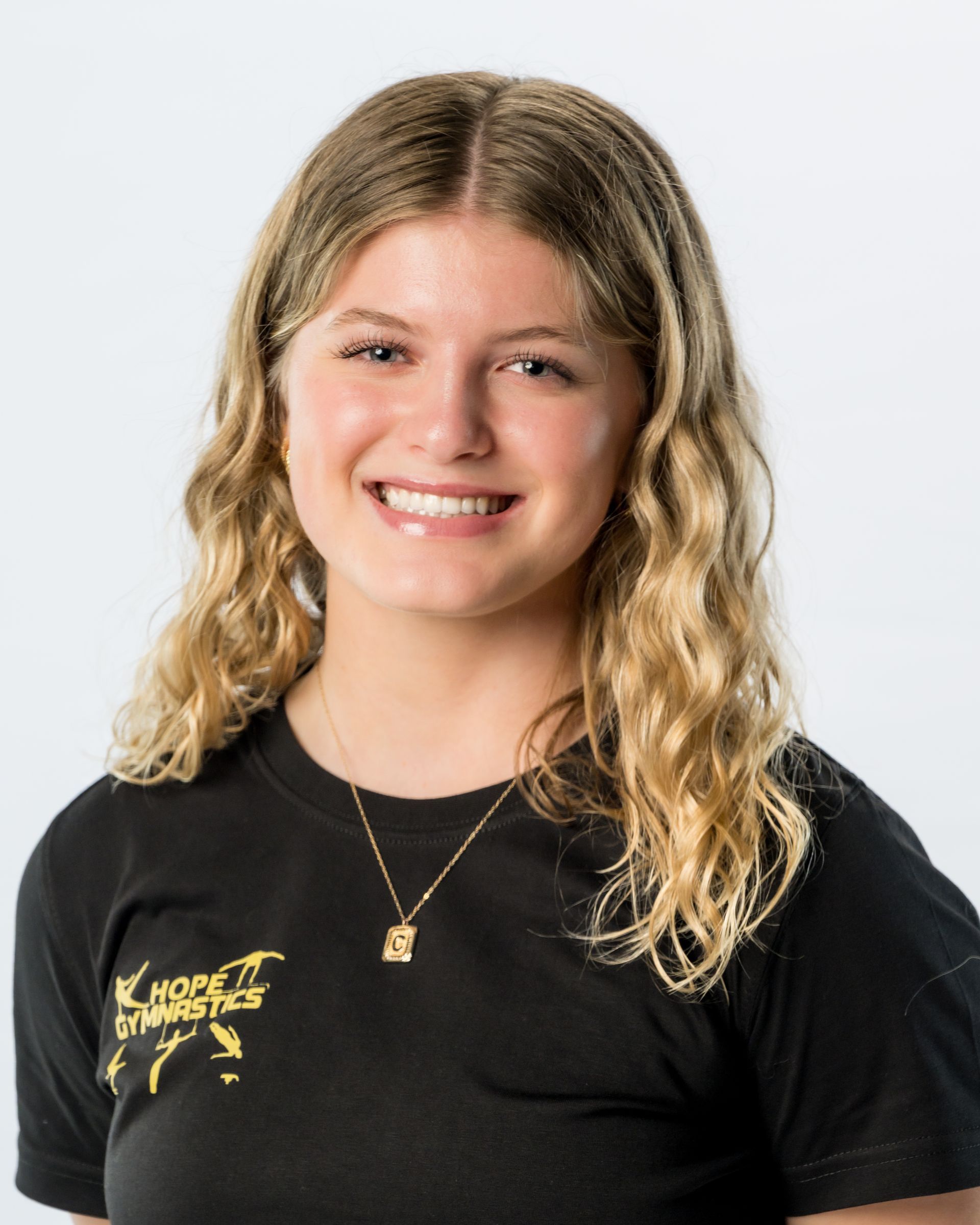 Smiling person in a black shirt against a light gray background.