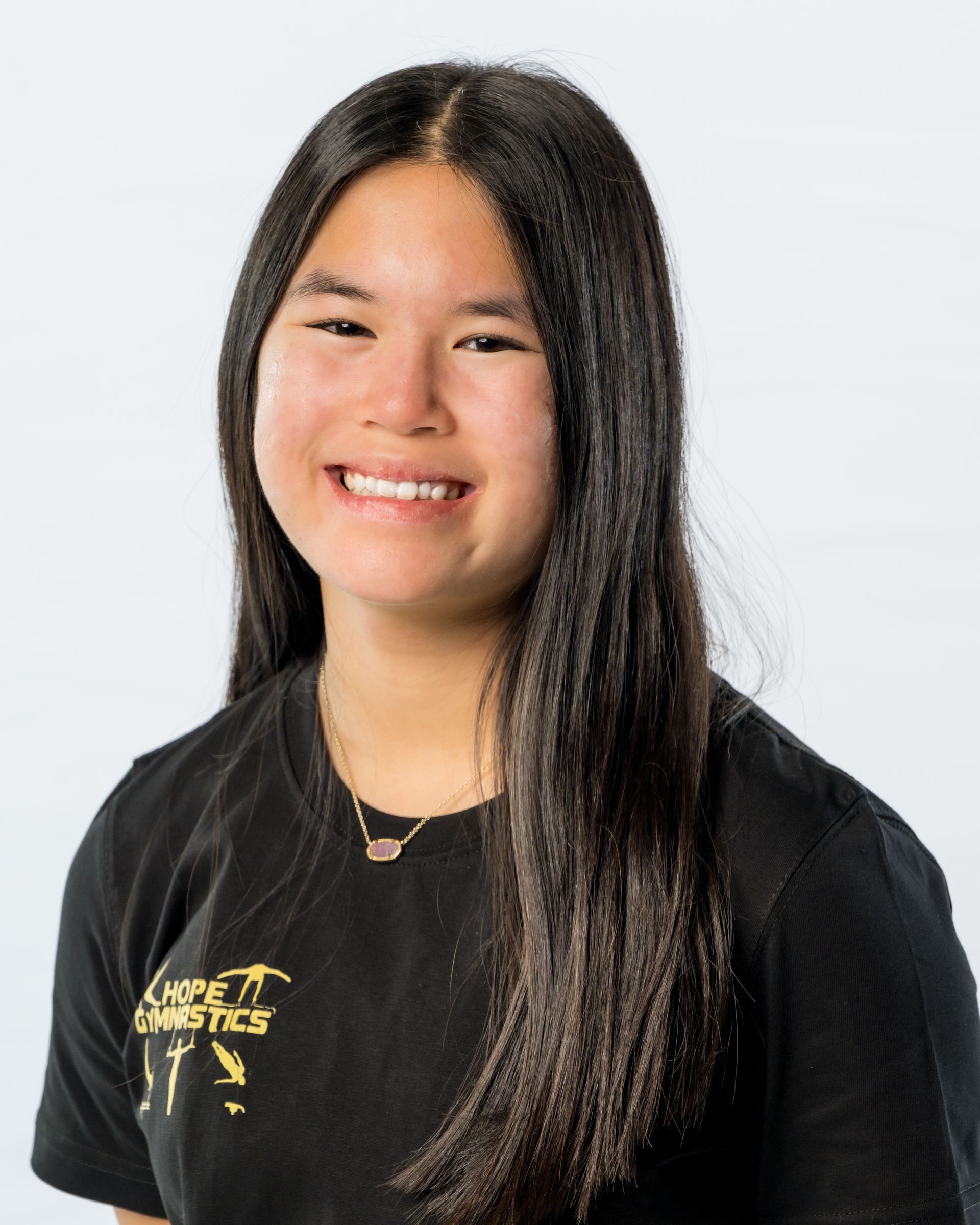 Smiling person in a black shirt against a light gray background.