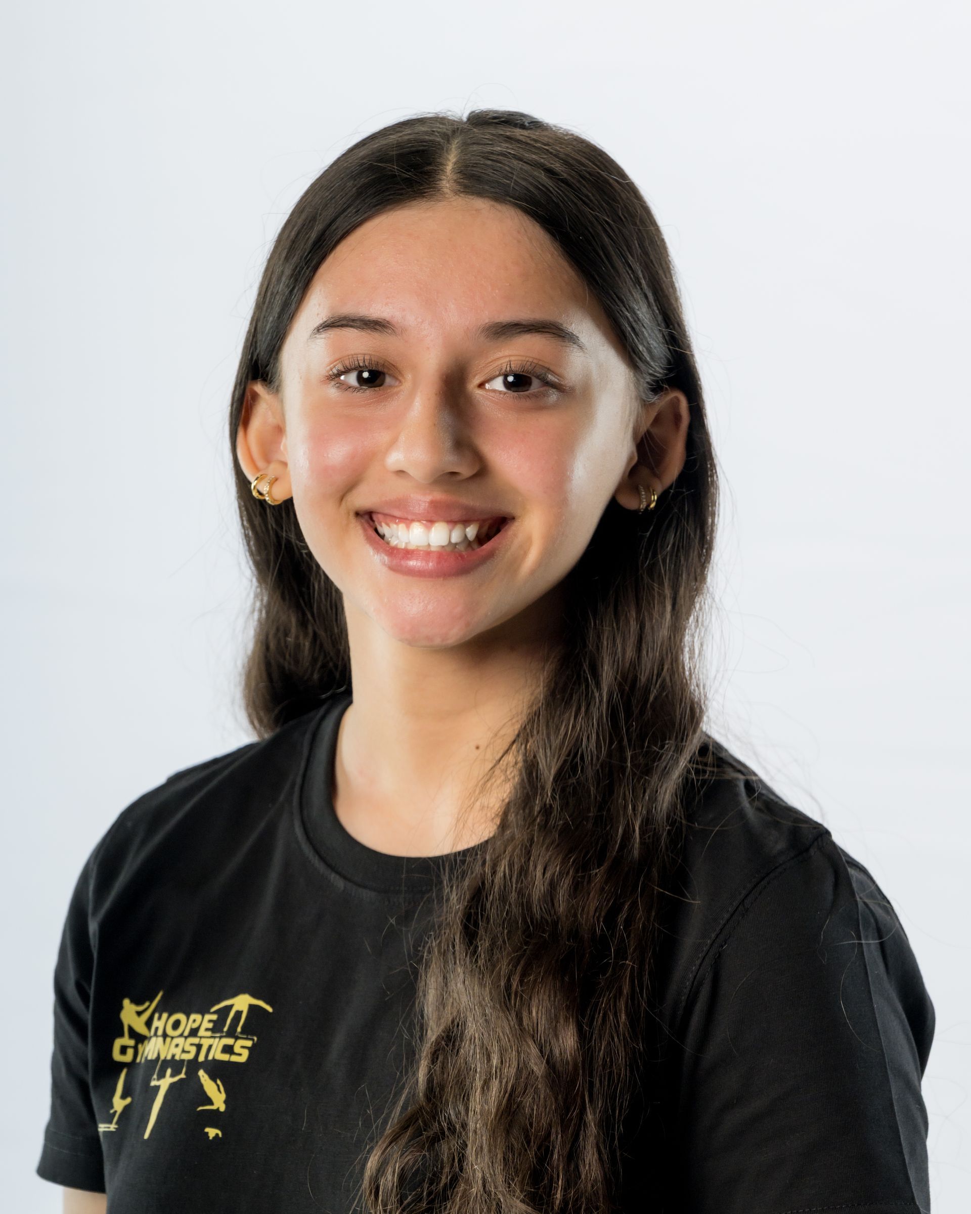 Smiling person with long dark hair wearing a black T-shirt against a light background