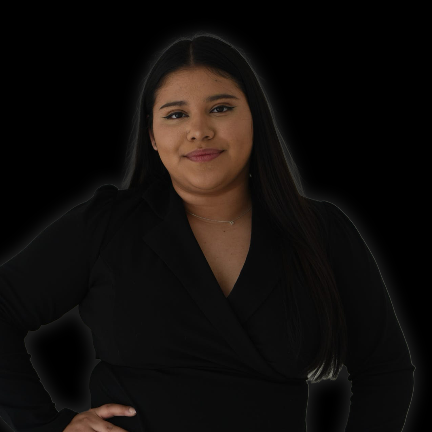 Woman in a black blazer posing against a dark background with a slight smile.