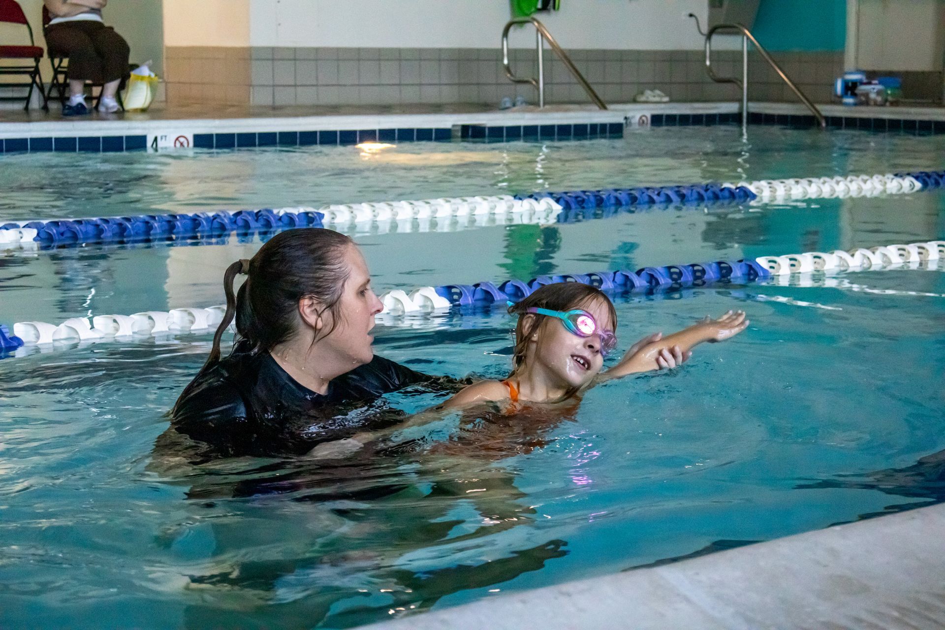 Swim instructor guiding a young swimmer through her freestyle stroke