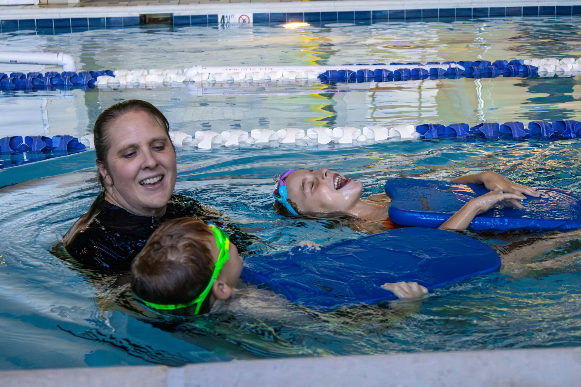 VSA swim instructor laughing with two young swimmers on kickboards