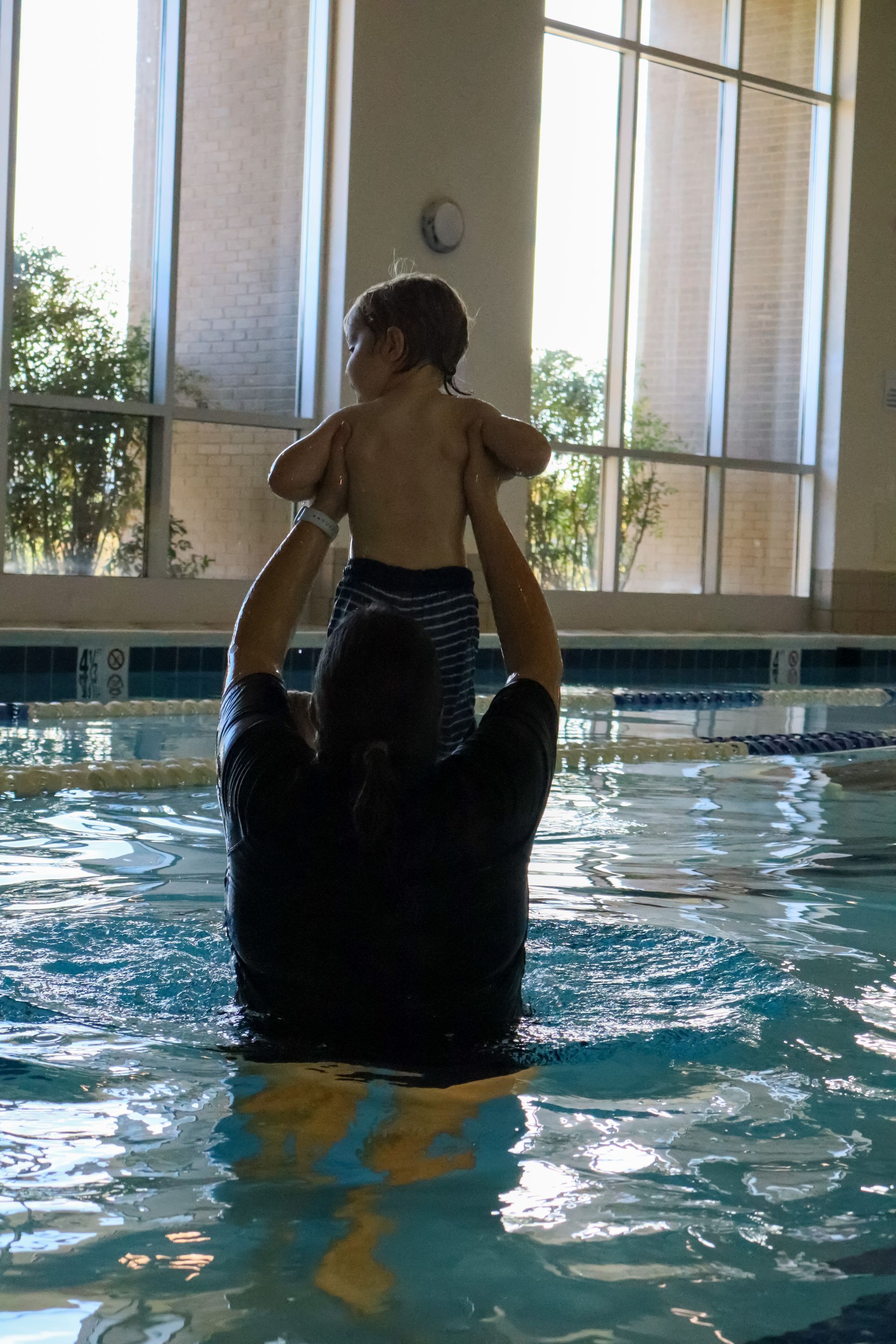 Swim instructor lifting a toddler during a Water Babies lesson