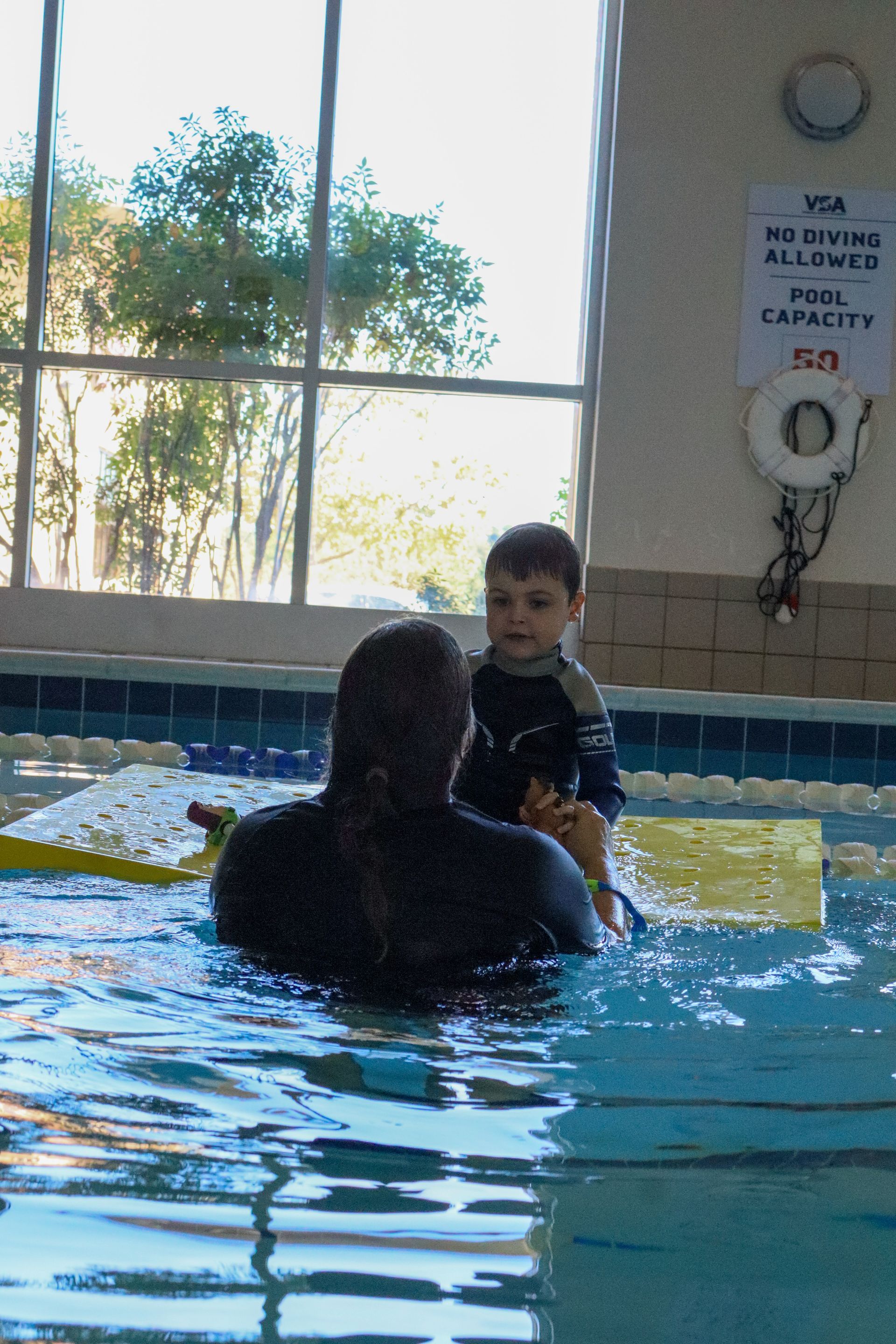 Young swimmer working with an instructor on a floating mat