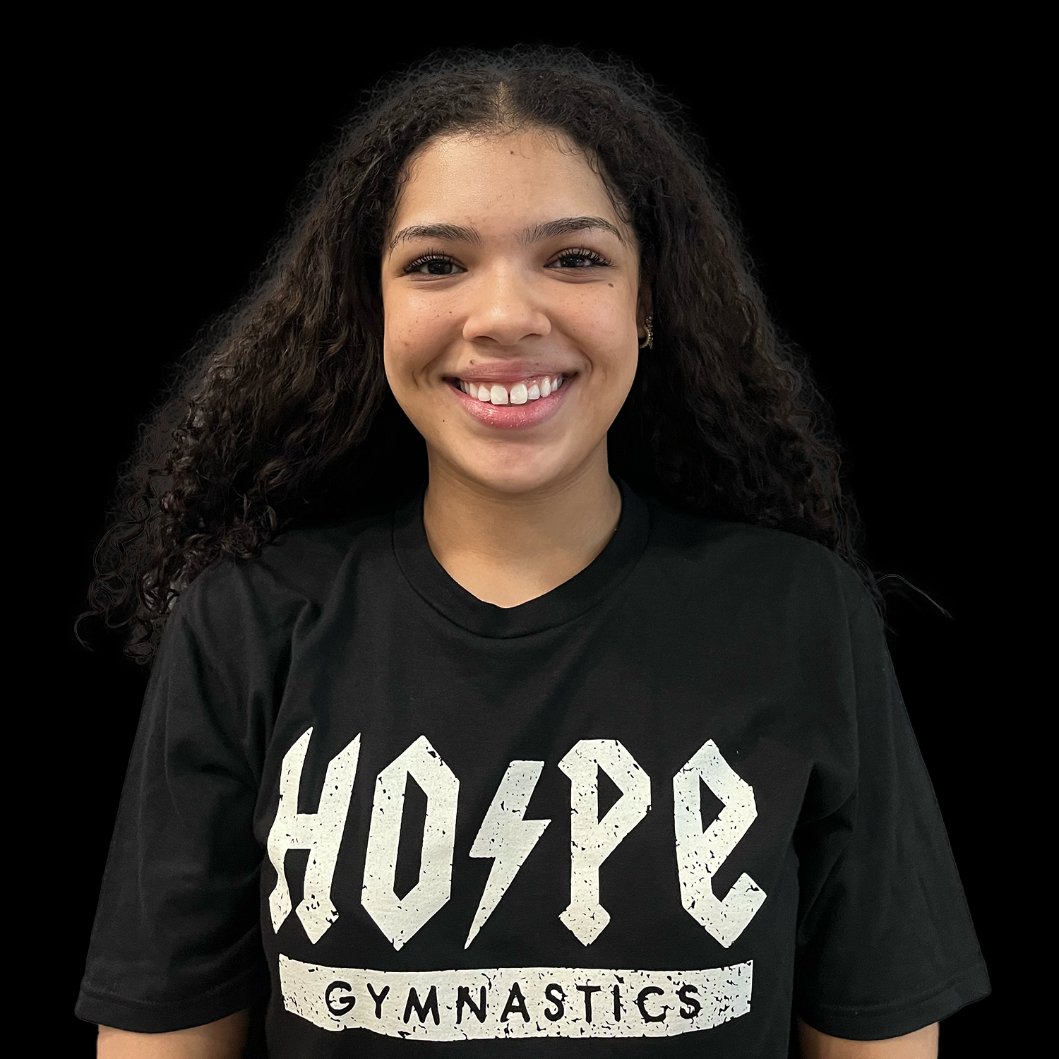 Smiling person in a black “HOPE GYMNASTICS” T-shirt against a black background