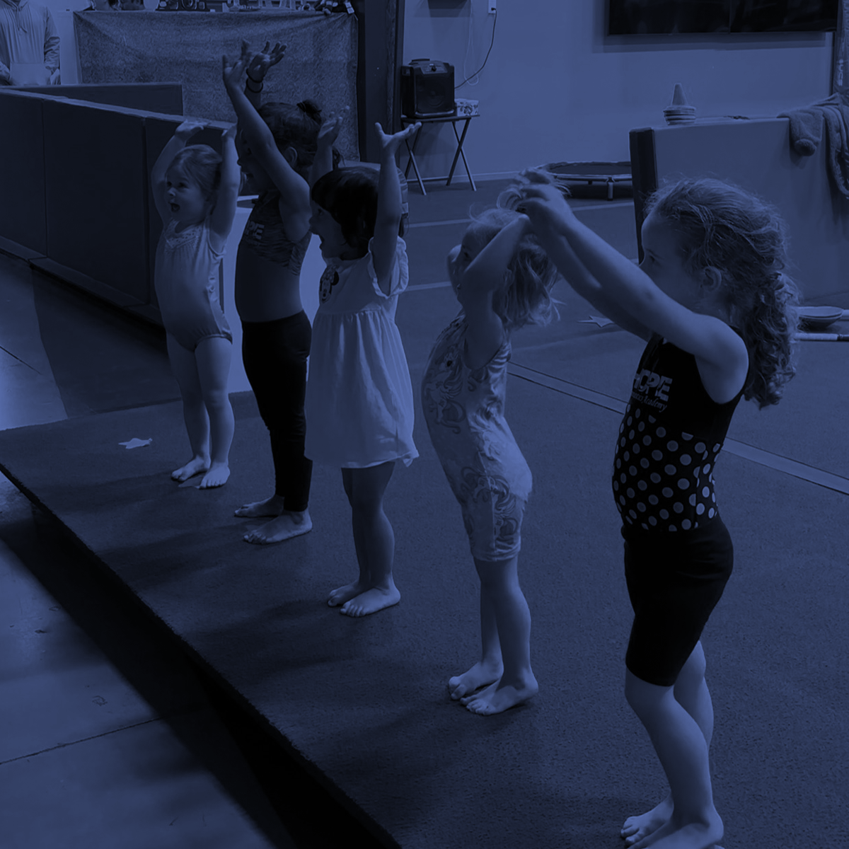 Four children stretching with arms raised in a dance studio