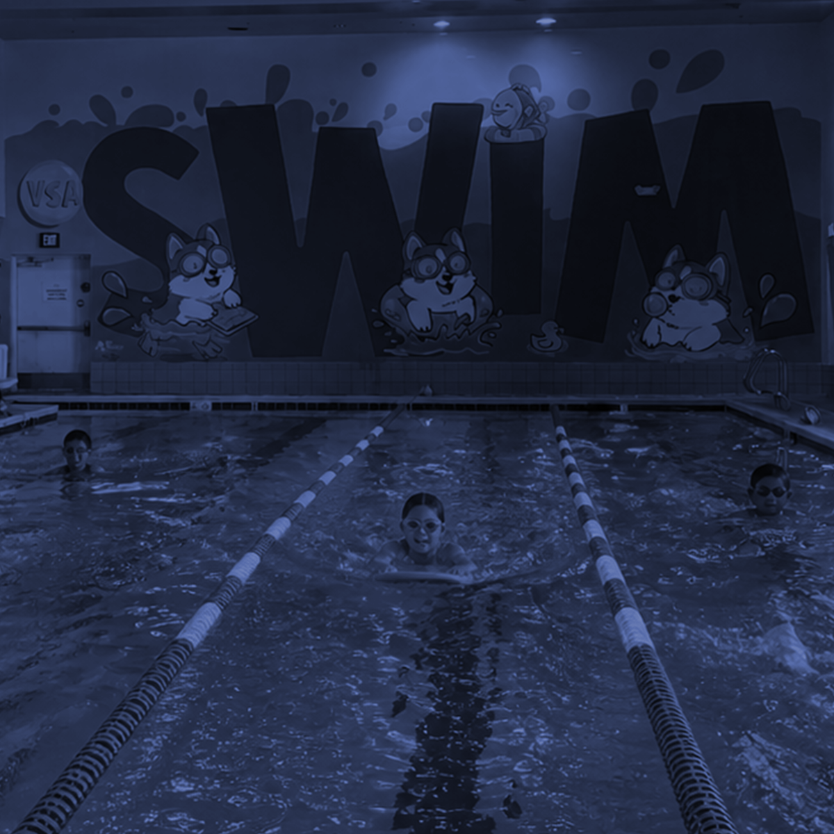 Indoor swimming pool with swimmers doing laps under a large wall mural of the letters “SWW”.
