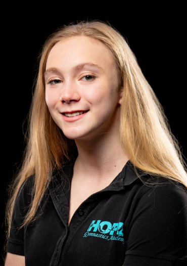 Smiling blonde woman in a black shirt with a turquoise logo on a black background
