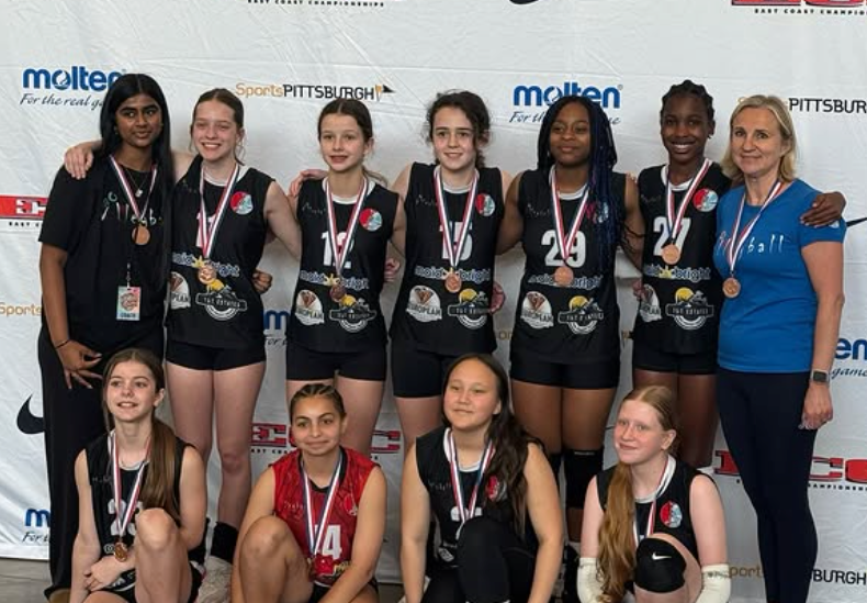 Volleyball team posing with medals and trophies in front of a sponsor backdrop