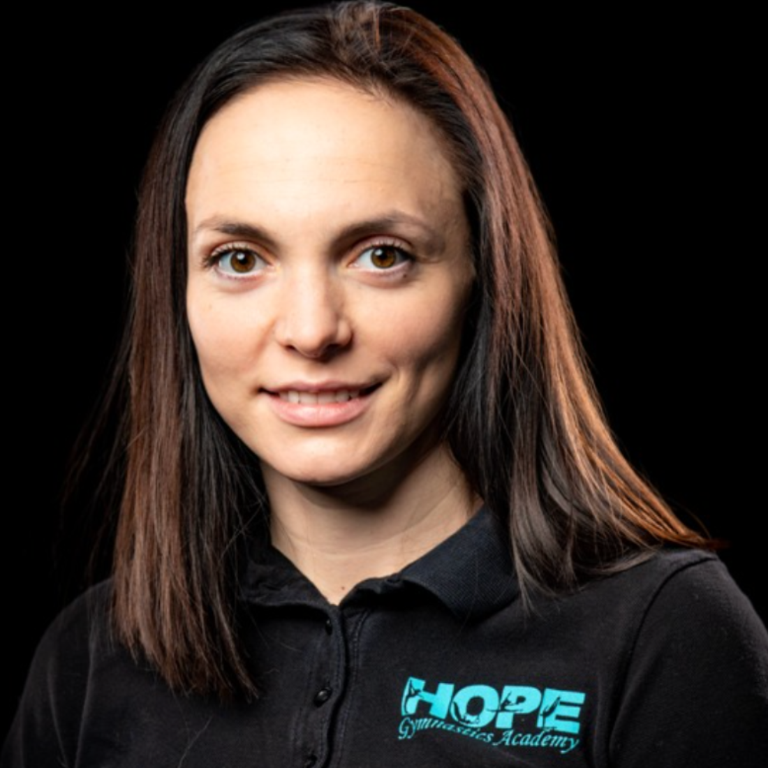 Portrait of a smiling woman in a black shirt with a turquoise HOPE logo against a dark background