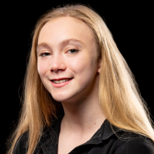 Portrait of a smiling blonde person in a black shirt against a dark background