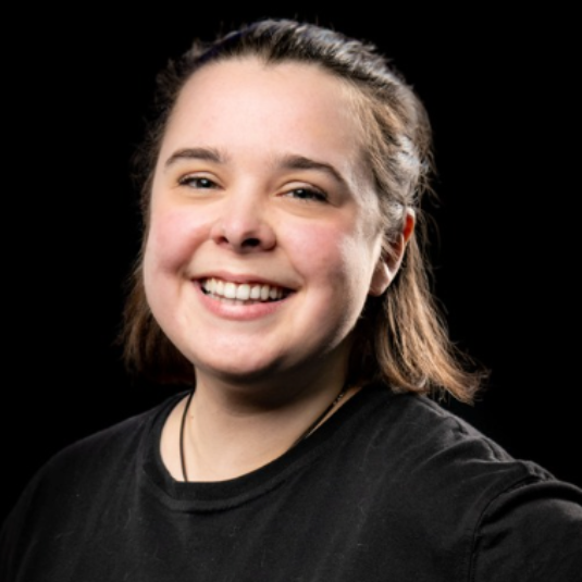 Smiling person in a black shirt against a dark background