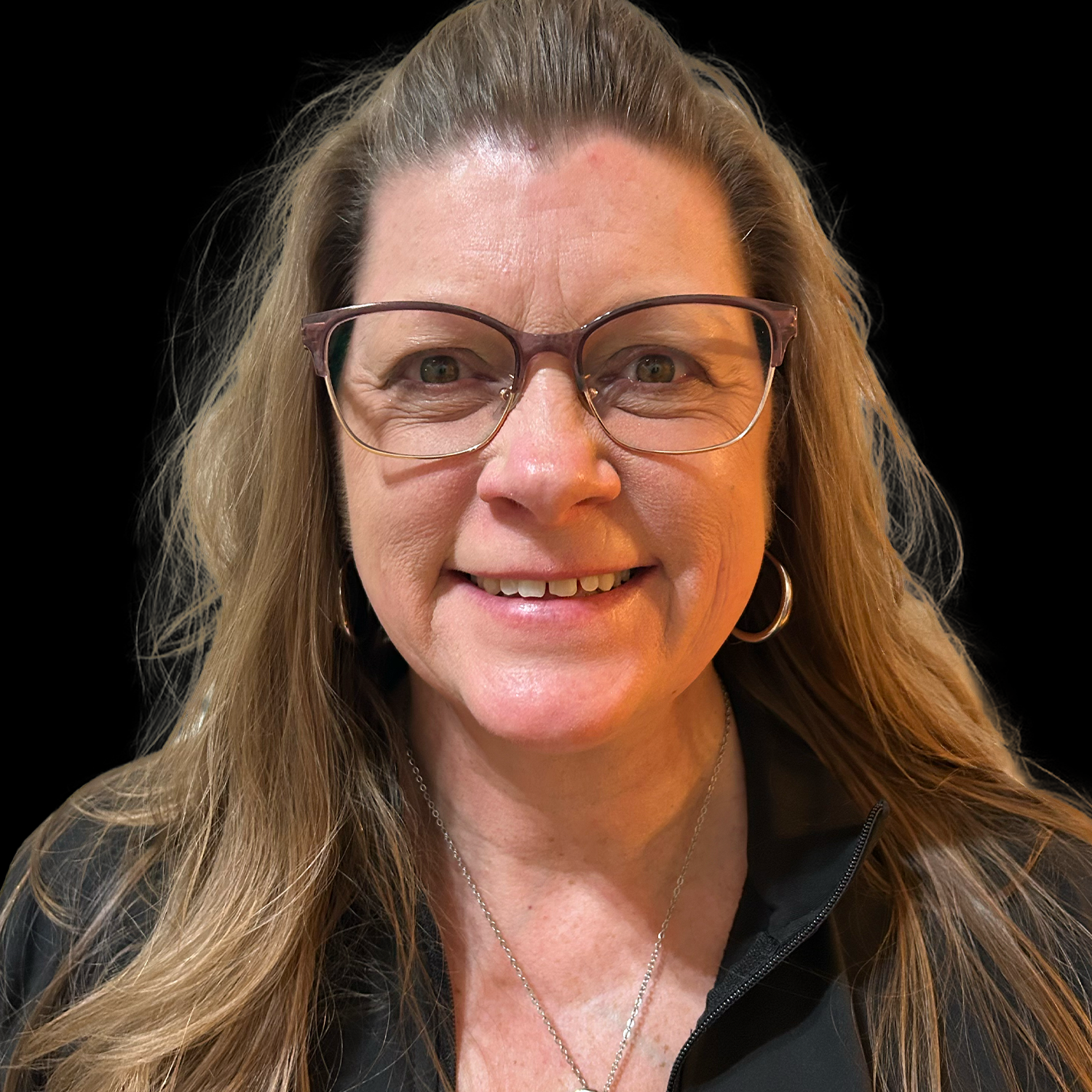 Smiling woman with glasses and long hair against a black background