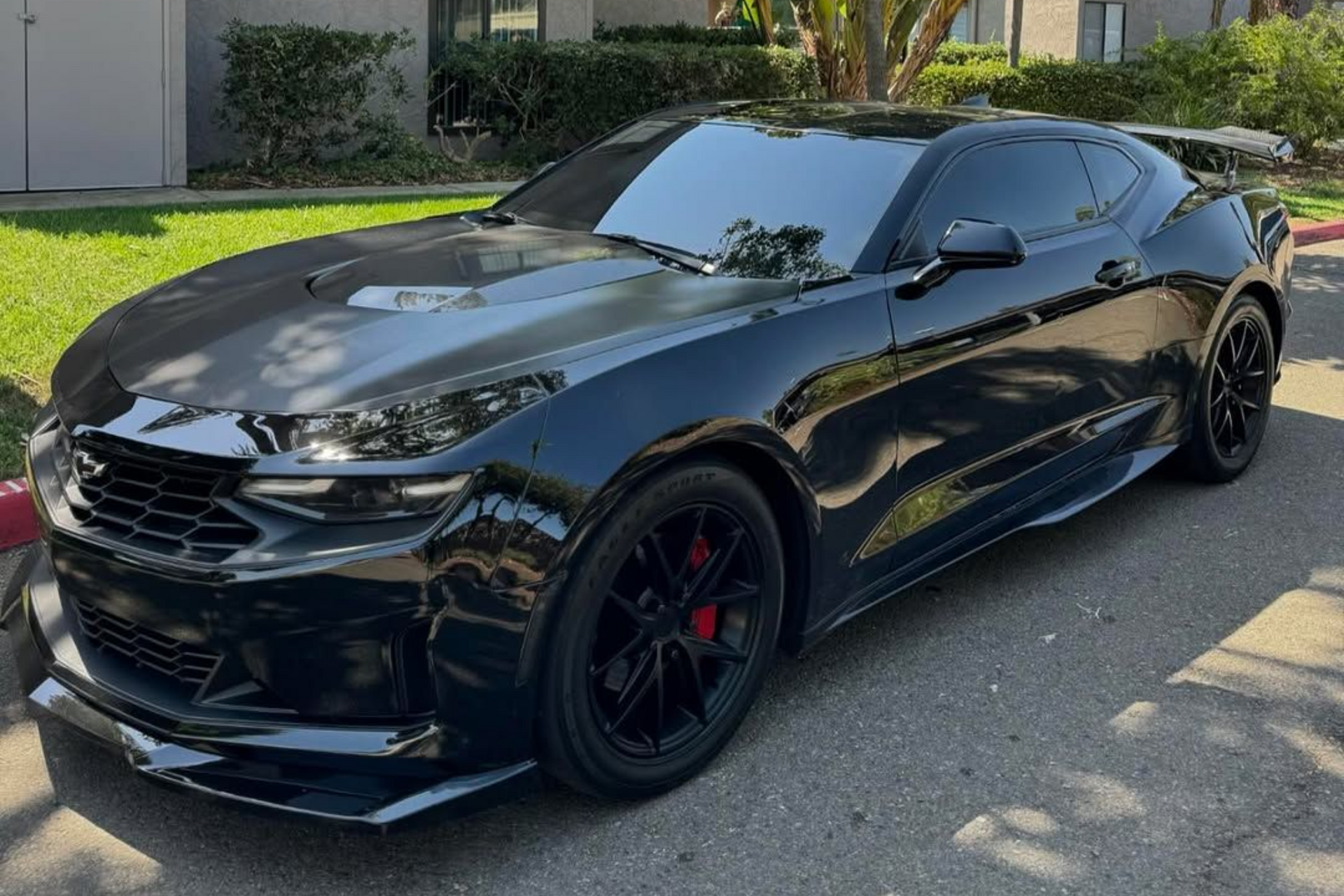 Black Chevrolet Camaro sports car parked on a paved road, front view, in a residential area.