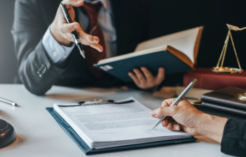 A man in a suit and tie is sitting at a desk with a clipboard and a pen.