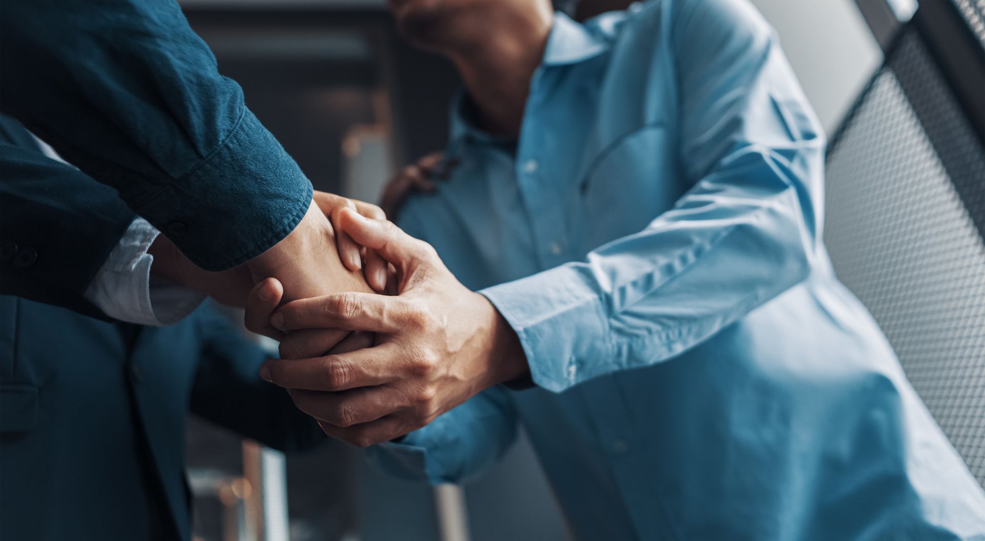 A man and a woman are shaking hands in an office.
