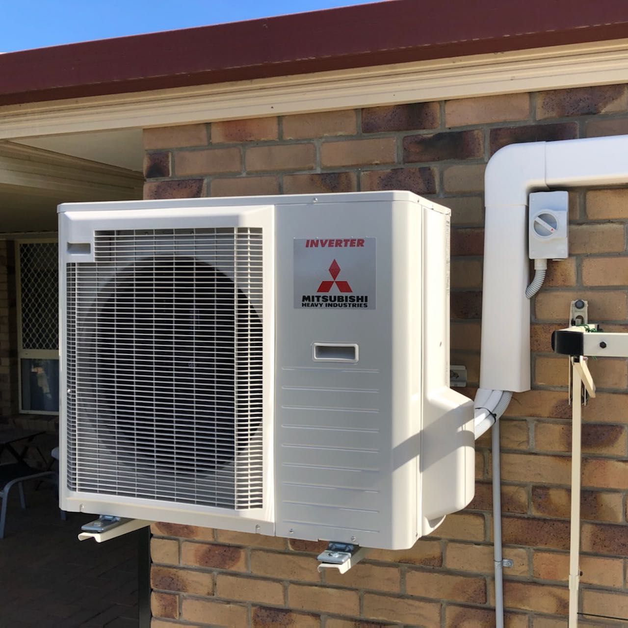 A White Air Conditioner Is Hanging on A Wall  — Paton's Electrical Services in Pialba, QLD