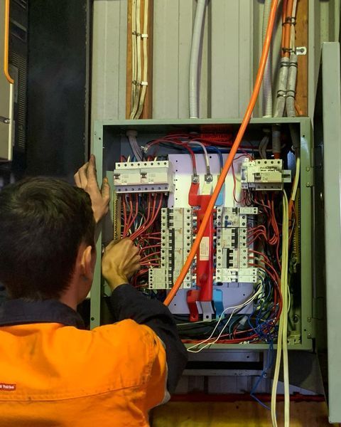 A Man In An Orange Vest Is Working On An Electrical Box — Paton's Electrical Services in Kawungan, QLD